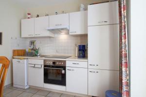 eine Küche mit weißen Schränken und einem Kühlschrank in der Unterkunft DW10a FeWo Diekkieker in Spieka-Neufeld