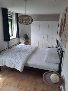 a bedroom with a large bed with white sheets and a table at Waterhuis Friesland in Oudwoude