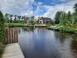 Oudwoude的住宿－Waterhuis Friesland，享有河流美景,拥有房屋的背景