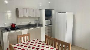 a kitchen with a table and a white refrigerator at Apartamento com área Gourmet Arroio do Silva in Arroio do Silva