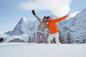 two people jumping in the snow in the mountains at Eiger Mürren Swiss Quality Hotel in Mürren