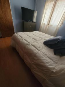 a bedroom with a white bed with a television and curtains at Departamento Completo y muy buena ubicación in Tandil