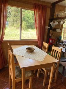 una mesa de madera y sillas en una cocina con ventana en Cabañas encanto del bosque, en Castro