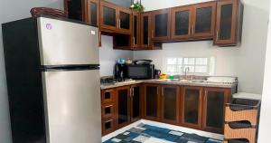 cocina con nevera y armarios de madera en Quiet Apartment, 3 Minutes From The Beach, 24H Security, Excellent Internet, en San Felipe de Puerto Plata