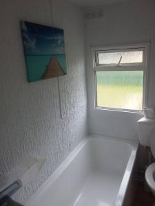 a white bathroom with a bath tub and a window at Rockets's Retreat in Bursledon