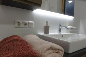 a white bathroom with a sink and a white sink at Apartment Lea in Maranza