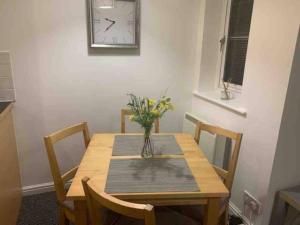 a dining room table with a vase of flowers on it at Modern Apartment in Barry Waterfront in Barry