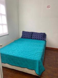 a bed with a blue comforter and pillows in a room at Hostal el Idilio in Cartagena