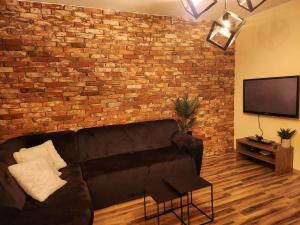 uma sala de estar com um sofá preto e uma parede de tijolos em Apartament P&P Prestige II em Inowrocław