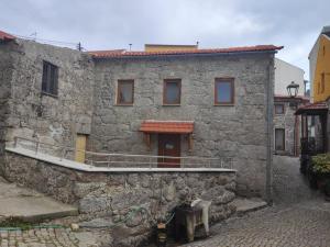 un edificio in pietra con balcone e porta di Casa dos Conchos Sabugueiro Casa com 4 quartos a Sabugueiro