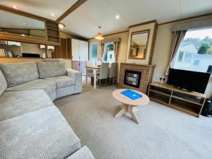 a living room with a couch and a tv and a table at Luxury 2 Bedroom Caravan LG13, Shanklin, Isle of Wight in Shanklin