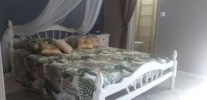 Schlafzimmer mit einem Bett mit einer grünen und weißen Bettdecke in der Unterkunft Résidence CARAÏBEA in Sainte-Luce