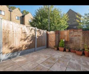 a backyard with a fence and some potted plants at Rainbow Quays in London