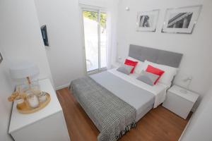 a white bedroom with a large bed with red pillows at Penthouse Exceptionnel vue Mer proche Monaco in Beausoleil
