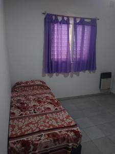 een bed in een kamer met paarse gordijnen bij Casa de campo Los Aloe in Cruz del Eje