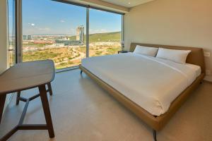 Schlafzimmer mit einem Bett, einem Schreibtisch und einem großen Fenster in der Unterkunft Park Life Querétaro in Querétaro