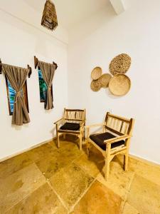 Zimmer mit 2 Stühlen und Hüten an der Wand in der Unterkunft Villa Mar Residence in Jericoacoara