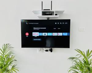 a flat screen tv hanging on a wall at Tirupati Homestay - Shilparamam - Luxury AC apartments by Stayflexi - Fast WiFi, Kitchen, Android TV - Walk to PS4 Pure Veg Restaurant - Easy access to Airport, Railway Station and to all Temples in Tirupati