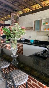 a vase of flowers on a counter in a kitchen at Sítio Maranata Vale das Montanhas in Monte Alegre do Sul