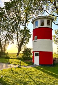 a red and white lighthouse in a field of grass at Liebevoll hinterm Deich - Ferienwohnungen in Lehe