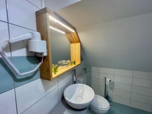 ein Badezimmer mit einem weißen WC und einem Spiegel in der Unterkunft Hotel ŠURC in Kranjska Gora