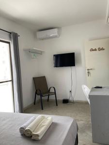 - une chambre avec un lit, une télévision et une chaise dans l'établissement Cantinho C - Alojamento Complementar, à Praia