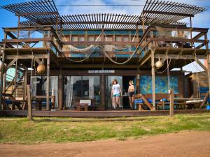 two people standing in front of a building at Mar de Fondo Hostel in Punta Del Diablo