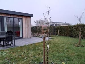 un jardín con una casa, una mesa y una valla en Luxe 5 persoons bungalow op rustig vakantiepark nabij Leeuwarden, en Dronrijp