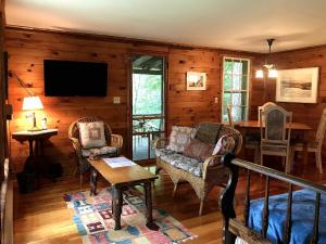 a living room with a couch and chairs and a television at Adirondack Cottage Retreat in Elizabethtown