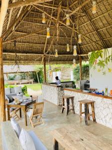 eine Terrasse mit einer Bar mit Tischen und Stühlen in der Unterkunft MITI Beach Bungalows in Nungwi