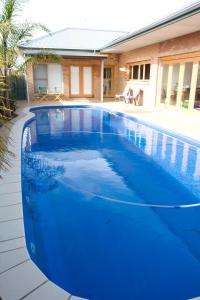 a blue swimming pool in front of a house at 94Best Apartments in Wagga Wagga
