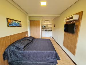 um quarto com uma cama e uma televisão em Condomínio Paraíso do Rosa em Imbituba