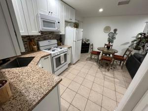 a kitchen with white appliances and a table with chairs at Casa de Abuelos, 2bd guest house, Jacuzzi, Biola, Disney, Knotts, LAX in Whittier