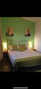 una camera da letto con un letto con pareti verdi e due lampade di Villa Bella Vista a Palermo