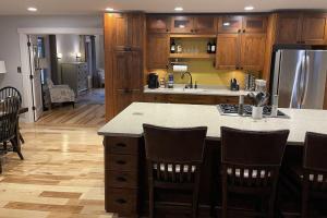 a kitchen with wooden cabinets and a kitchen island with chairs at The Retreat by On Cue Properties 