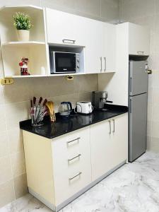 a kitchen with white cabinets and a black counter top at شقه رائعه باطلاله ساحره تواصل قبل الحجز in Cairo