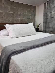 a bedroom with a white bed with a brick wall at Casa del Café - Loft in Heredia