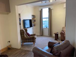 a living room with a couch and chairs and a television at Hope Corner in Filey