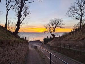 a path next to the ocean with a sunset in the background at Hope Corner in Filey