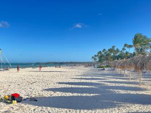 Stanza Mare Beach Front في بونتا كانا: شاطئ فيه صف من المظلات والناس عليه