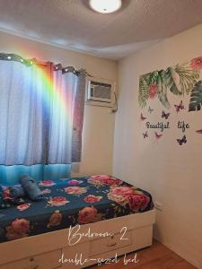 a bedroom with a bed with a rainbow on the wall at Seawind Condominium 2BR unit in Davao City