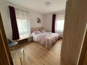 a small bedroom with a bed and two windows at Stanjkov smještaj in Donji Kraljevec