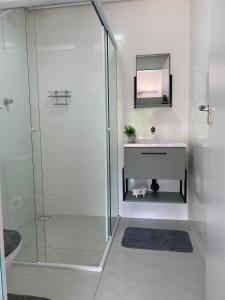 a bathroom with a shower with a sink and a mirror at Studio Recanto Beach Itapema in Itapema