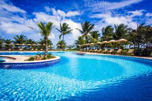uma piscina no resort com palmeiras e guarda-sóis em Vila Angatu Eco Resort SPA em Santo André