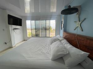a bedroom with a large white bed with a window at Luna Roja casa Frente al Mar y glamping in San Onofre