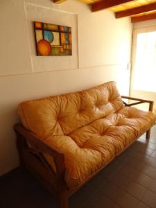 un sofá de cuero marrón en una habitación con una pintura en Del Valle Apartamentos 285 en Valle Hermoso