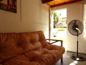 un sofá de cuero marrón en la sala de estar con ventilador en Del Valle Apartamentos 285 en Valle Hermoso
