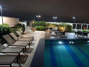 a patio with chairs and a swimming pool at night at Studio 1202 Guarulhos Aeroporto in Guarulhos