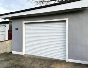 una puerta de garaje al lado de una casa en Boutique Backyard Bungalow - Brimsdown, en Enfield Lock