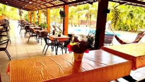 a patio with tables and chairs and a pool at Pousada Sol Nascente ll in Olímpia